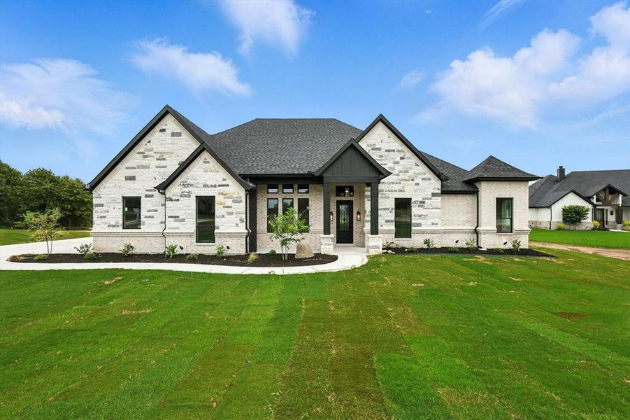 View of front facade with a front lawn, brick siding, and stone siding View of front facade with a front lawn, brick siding, and stone siding