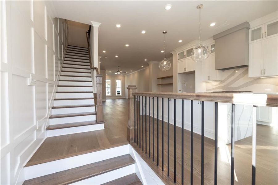 Stairs with wood finished floors, recessed lighting, a ceiling fan, and ornamental molding
