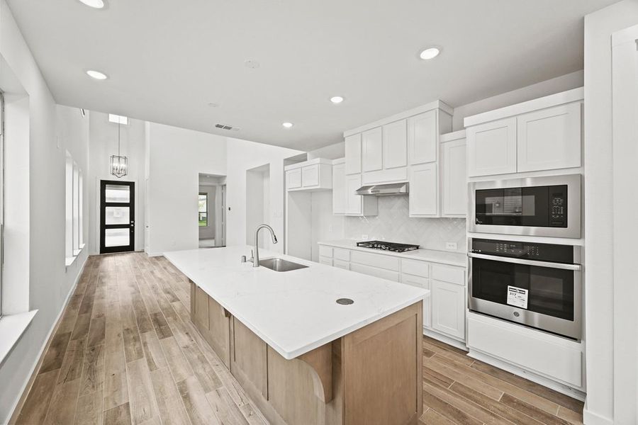 The kitchen features bright white cabinetry and a large central island, creating a welcoming space to cook, entertain, and gather. The kitchen features bright white cabinetry and a large central island, creating a welcoming space to cook, entertain, and gather.