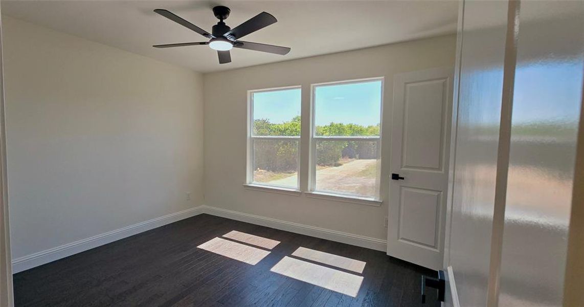 Unfurnished room featuring ceiling fan and dark wood-type flooring Unfurnished room featuring ceiling fan and dark wood-type flooring