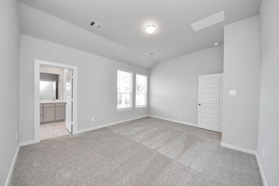 Escape and relax in the exquisite primary suite, a haven to unwind after a long day. The spacious room, located on first floor, boasts plush carpeting, soothing paint tones, high ceilings, and expansive windows adorned with privacy blinds. Sample photo of completed home with similar floor plan. Actual colors and selections may vary.