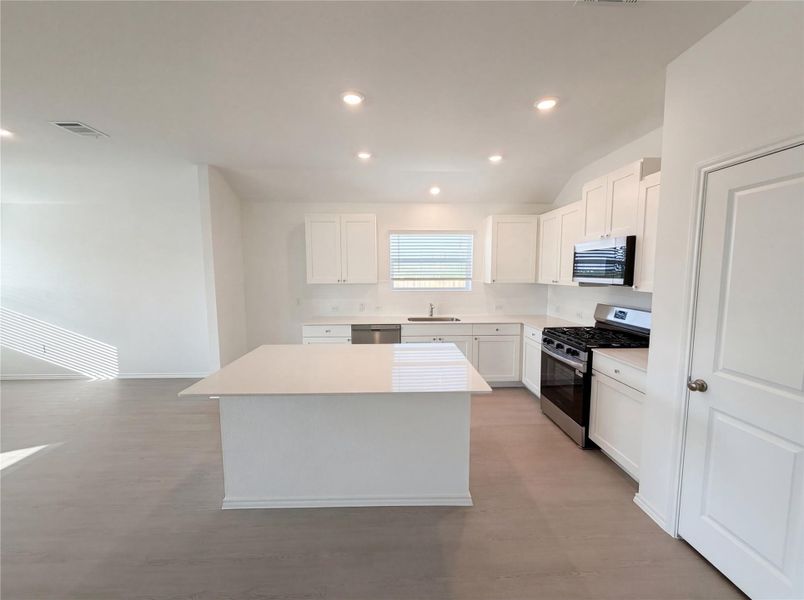 Kitchen featuring stainless steel appliances, white cabinetry, a center island, recessed lighting, and light wood-style flooring