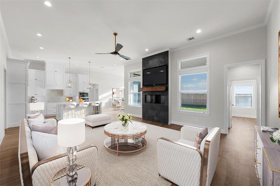 Living area featuring ceiling fan, dark wood-style flooring, crown molding, recessed lighting, and a large fireplace Living area featuring ceiling fan, dark wood-style flooring, crown molding, recessed lighting, and a large fireplace