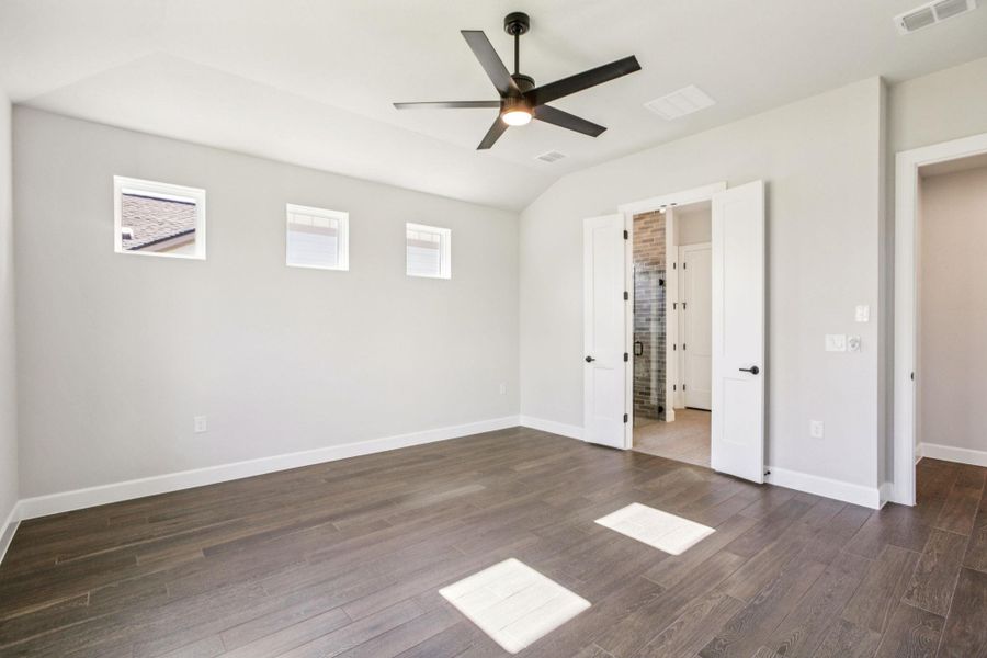 Unfurnished bedroom featuring dark wood-type flooring, ceiling fan, and vaulted ceiling Unfurnished bedroom featuring dark wood-type flooring, ceiling fan, and vaulted ceiling