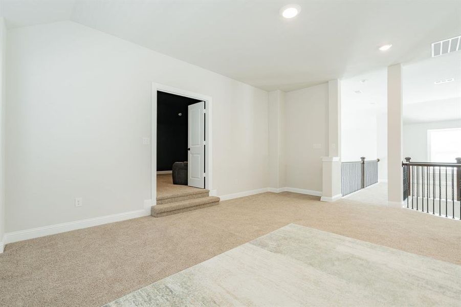 Carpeted empty room featuring visible vents, baseboards, recessed lighting, and vaulted ceiling