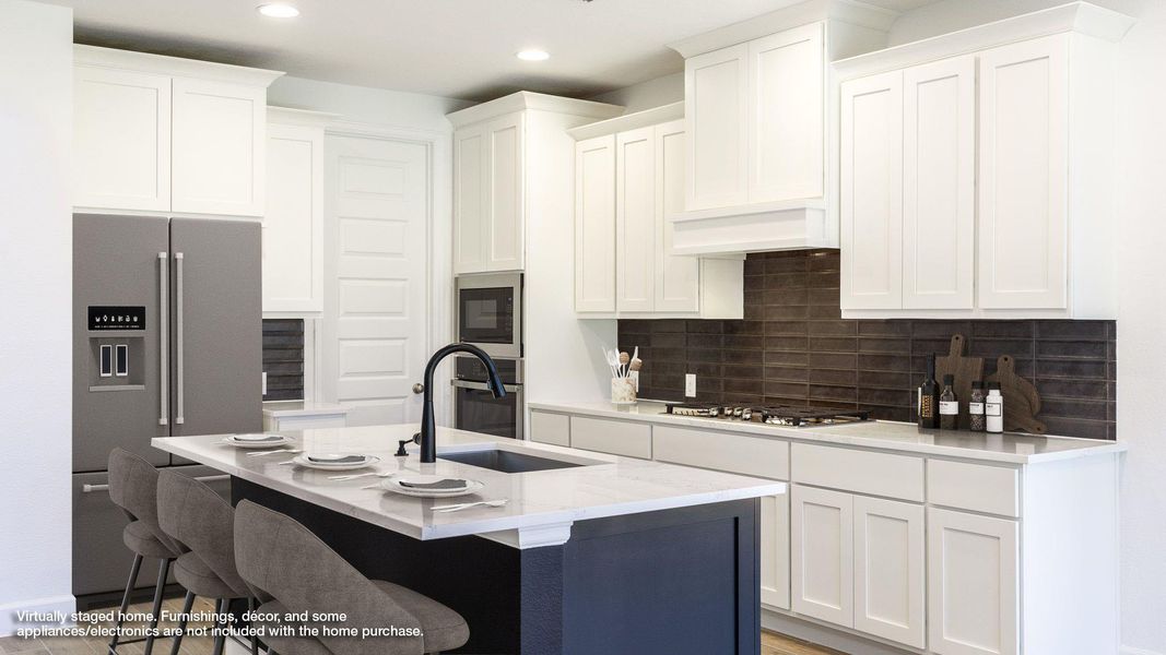 Kitchen with a kitchen breakfast bar, appliances with stainless steel finishes, white cabinetry, light stone counters, and an island with sink