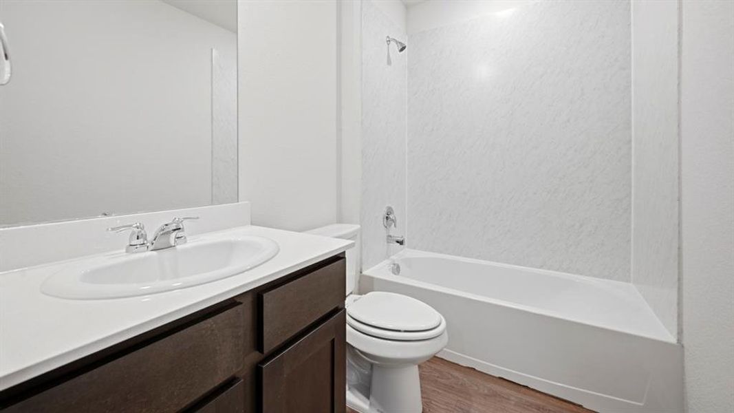 Full bathroom featuring vanity, washtub / shower combination, and dark wood-type flooring Full bathroom featuring vanity, washtub / shower combination, and dark wood-type flooring