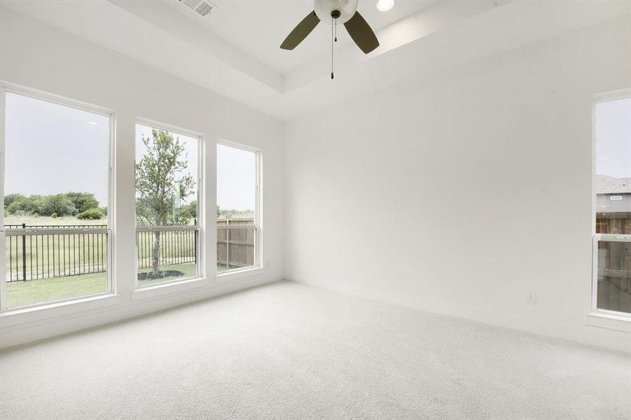 Spacious room featuring a tray ceiling, ceiling fan with integrated lighting, recessed lighting, and light-toned carpet flooring