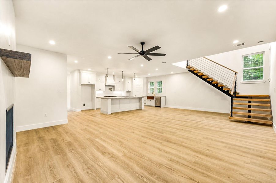 Spacious open-concept living area with a modern kitchen featuring an 11 foot  island, and a stylish staircase leading to the upper level.