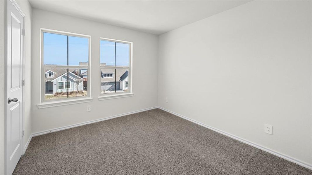 Spare room featuring dark carpet and baseboards