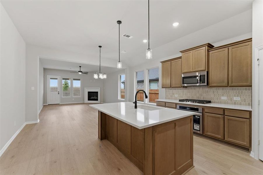Spacious kitchen featuring a central island with quartz countertop, stainless steel appliances, and wood-finish cabinetry