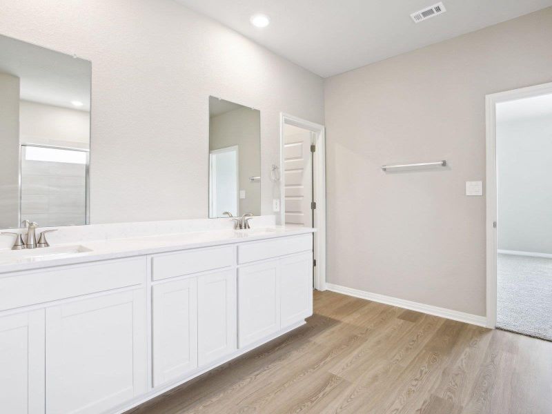 Full bathroom with double vanity, wood finished floors, baseboards, and a shower Full bathroom with double vanity, wood finished floors, baseboards, and a shower