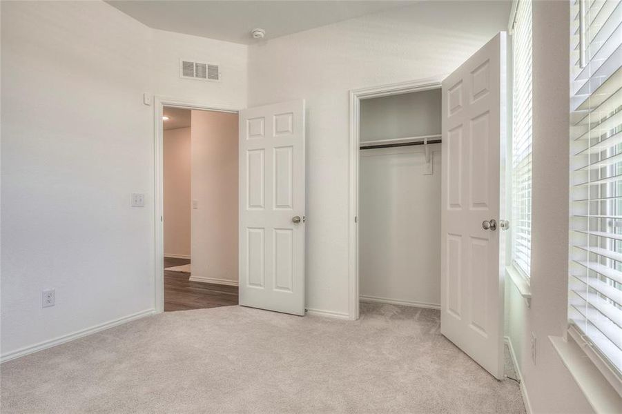 Unfurnished bedroom featuring light carpet and a closet Unfurnished bedroom featuring light carpet and a closet