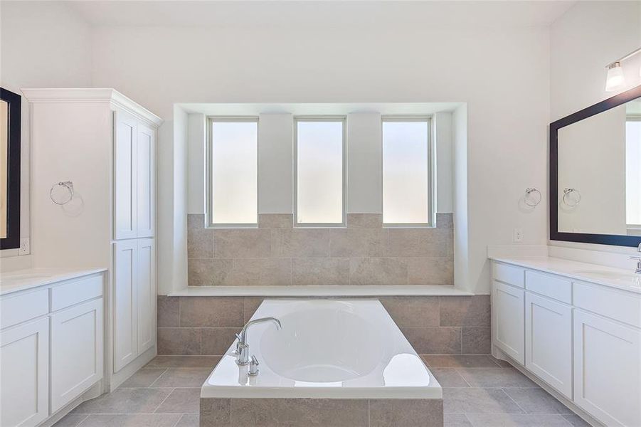 Bathroom with tile patterned flooring, tiled tub, and vanity