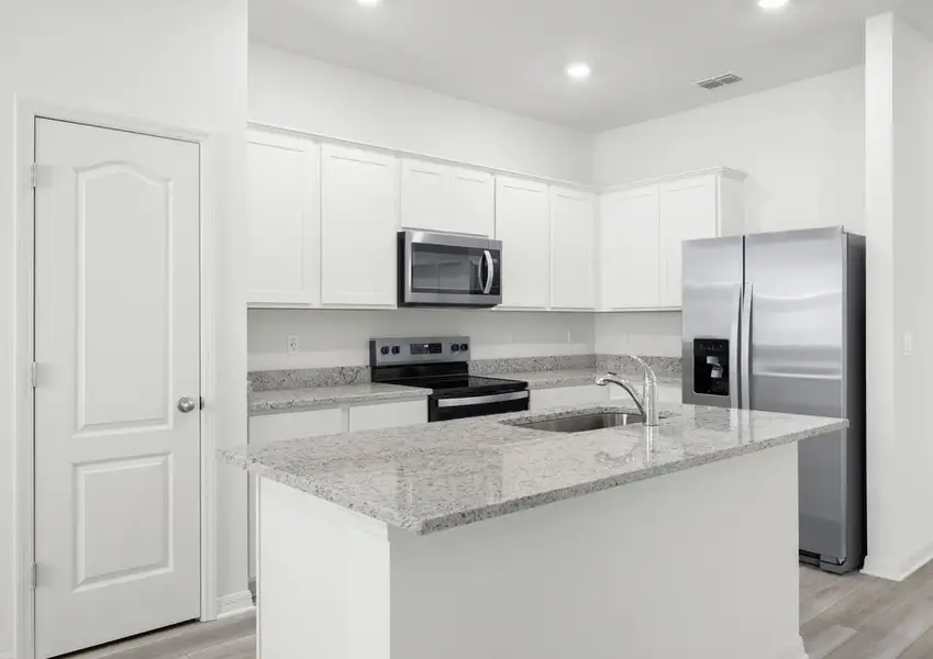 Kitchen in the Braden - FL home in Fort Pierce, featuring the range, microwave, and refrigerator.