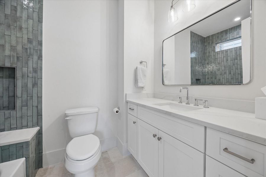 3rd floor secondary bathroom with natural stone tile floors and marble countertops.