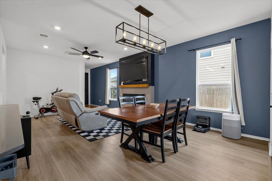 An inviting family room flows into the dining area, featuring a cozy fireplace and contemporary lighting.