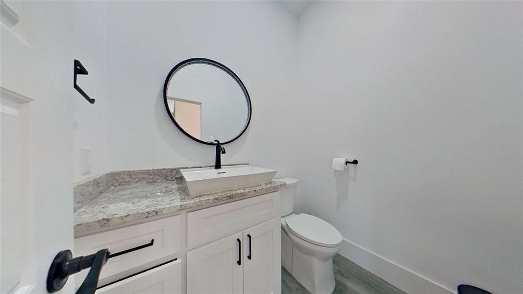 Powder room featuring a white floating vessel sink, matte black faucet, and a round framed mirror Powder room featuring a white floating vessel sink, matte black faucet, and a round framed mirror