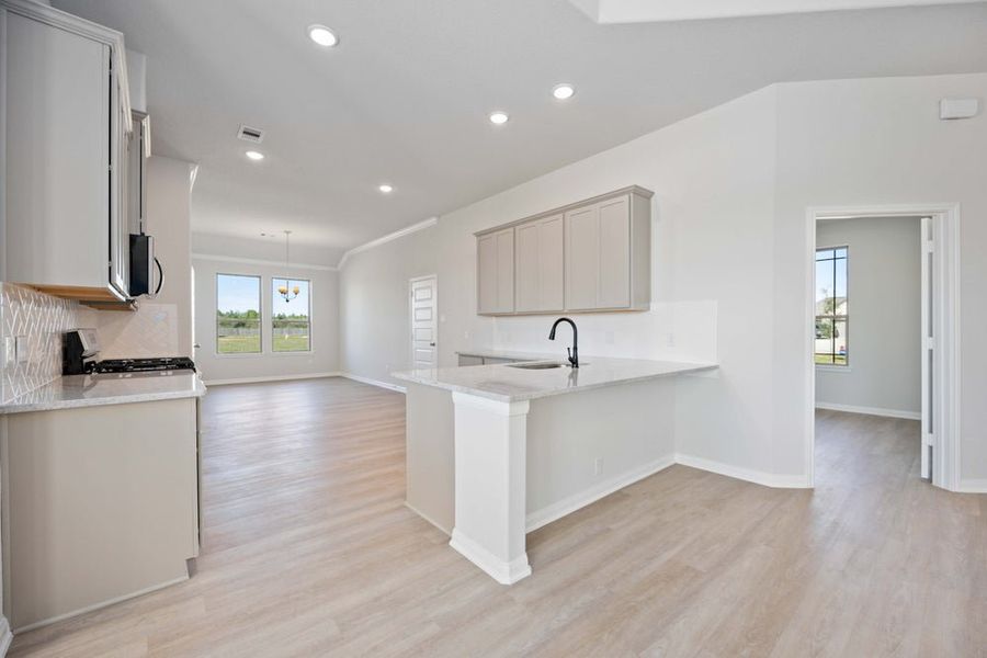 Open-concept kitchen with white island, gray cabinets, and light wood flooring