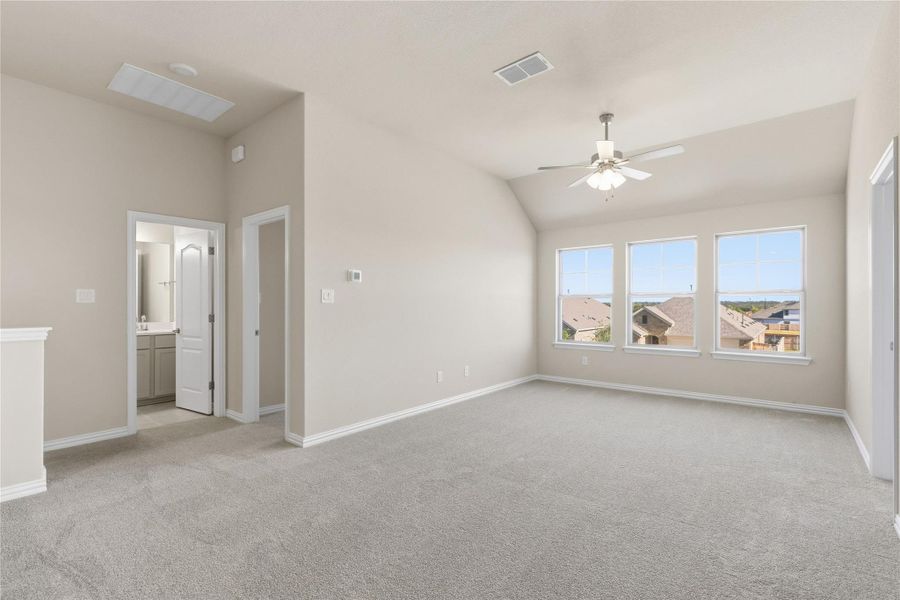 Spare room featuring light carpet, vaulted ceiling, and ceiling fan