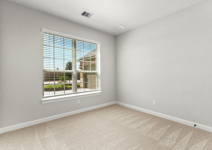 A secondary bedroom with a large window overlooking the front yard