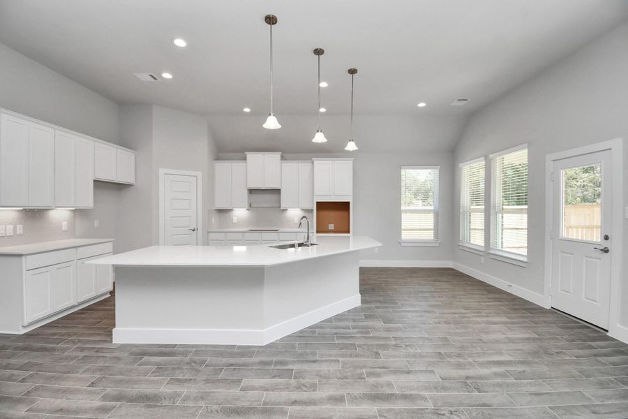 The kitchen is a culinary haven, featuring granite countertops, a tile backsplash, stainless steel appliances, 42” upper cabinets, and undercabinet lighting. Sample photo of completed home with similar floor plan. Actual colors and selections may vary. The kitchen is a culinary haven, featuring granite countertops, a tile backsplash, stainless steel appliances, 42” upper cabinets, and undercabinet lighting. Sample photo of completed home with similar floor plan. Actual colors and selections may vary.