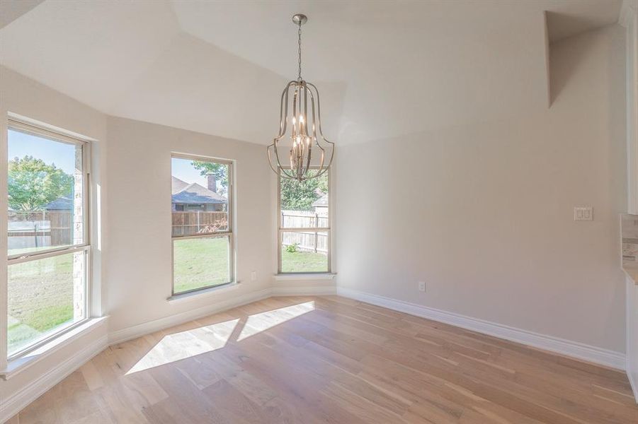 Empty room featuring light hardwood / wood-style flooring, a healthy amount of sunlight, and a notable chandelier