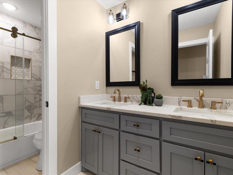 Bathroom featuring double vanity and shower / bath combination with glass door