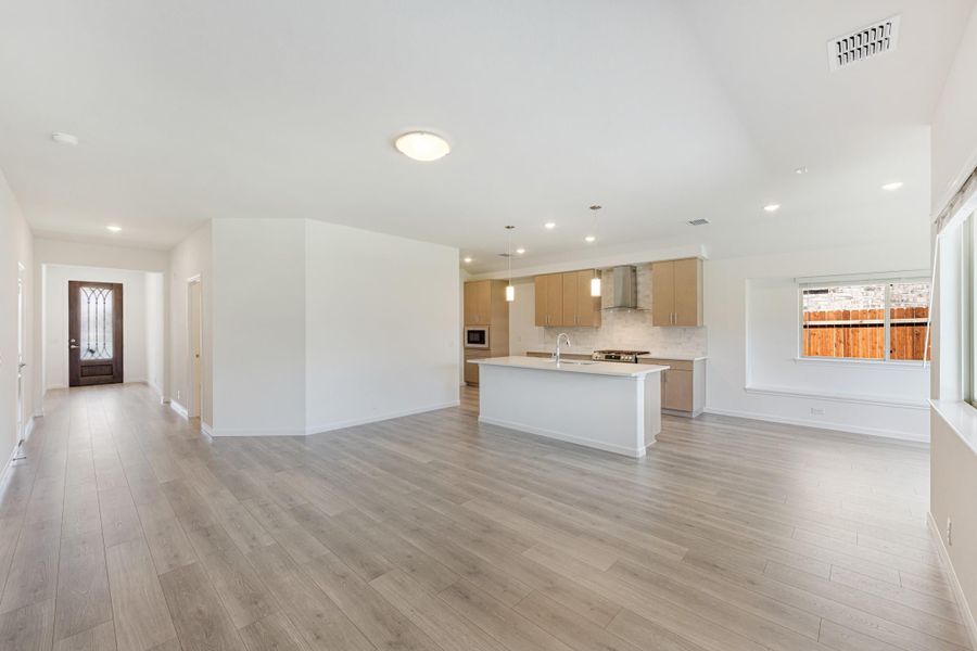 Open-concept living area with kitchen island, light wood cabinets, and gray hardwood floors Open-concept living area with kitchen island, light wood cabinets, and gray hardwood floors