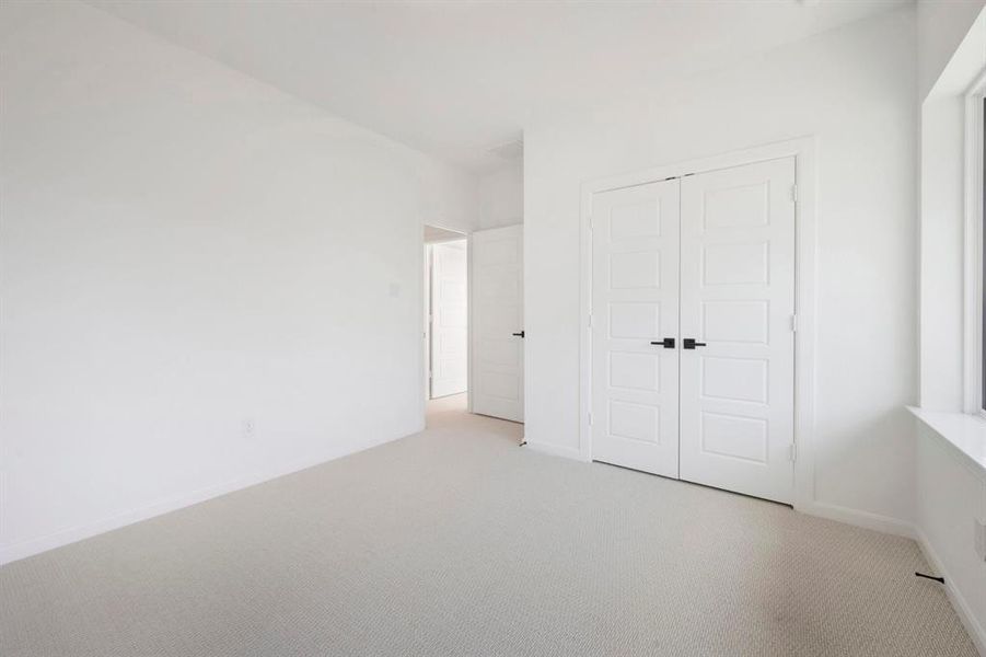 Bright room featuring light-toned carpeting, white walls, and a large window with dark trim