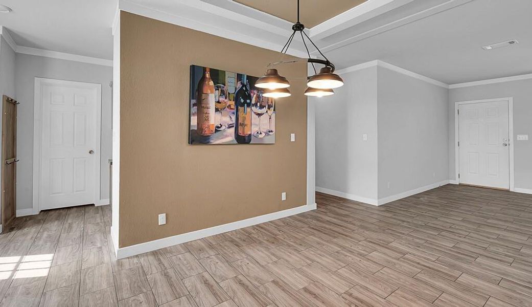 Empty room with ornamental molding, wood finished floors, and a chandelier Empty room with ornamental molding, wood finished floors, and a chandelier