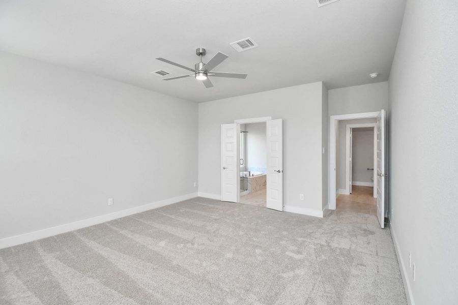 Escape and relax in the exquisite primary suite, a haven to unwind after a long day. The spacious room, boasts plush carpeting, soothing paint tones, high ceilings, and expansive windows adorned with privacy blinds. Sample photo of completed home with similar floor plan. Actual colors and selections may vary.