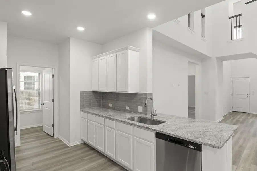 Kitchen featuring white cabinets, stainless steel appliances, light stone countertops, light wood-style flooring, and recessed lighting Kitchen featuring white cabinets, stainless steel appliances, light stone countertops, light wood-style flooring, and recessed lighting