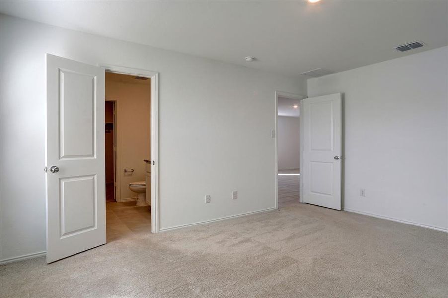 Unfurnished bedroom featuring light colored carpet and ensuite bathroom
