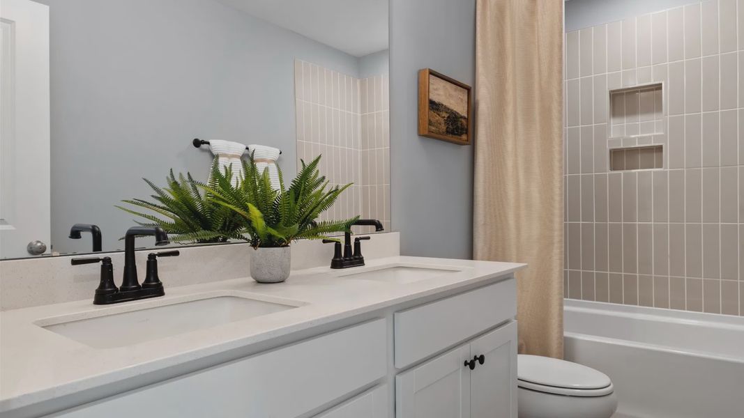 Stonefield home plan secondary bathroom with dual vanities and tile shower Stonefield home plan secondary bathroom with dual vanities and tile shower