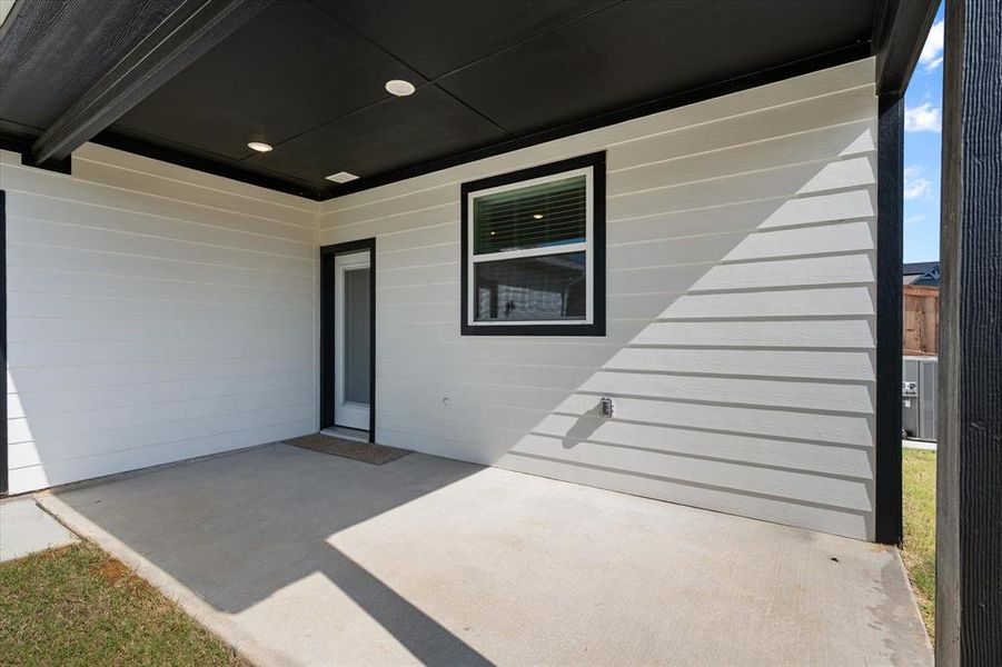 View of the covered back patio, with recessed lighting and rain gutters, overlooking the backyard.