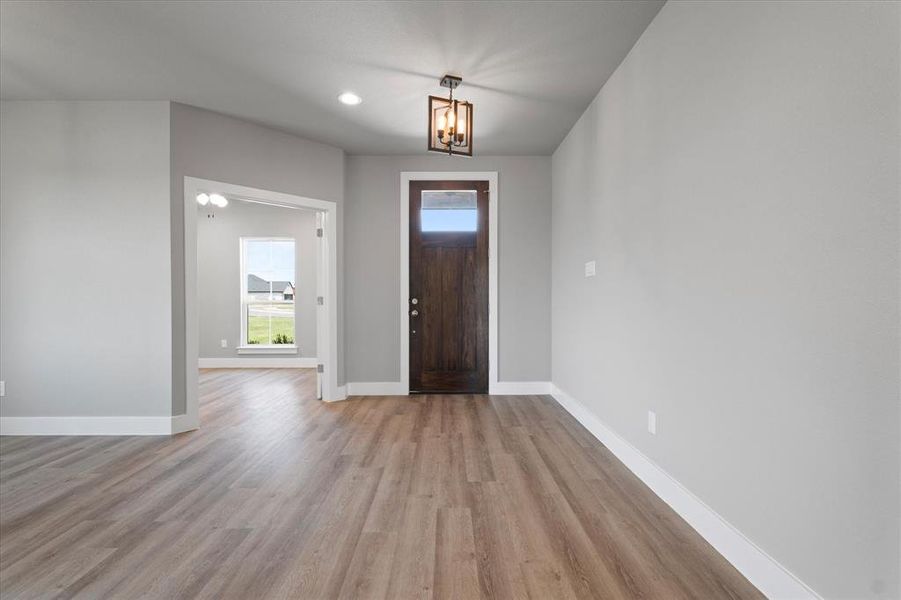 Foyer entrance with an inviting chandelier and light wood-type flooring