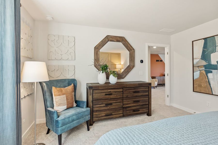 A bedroom with a mirror and a chair.