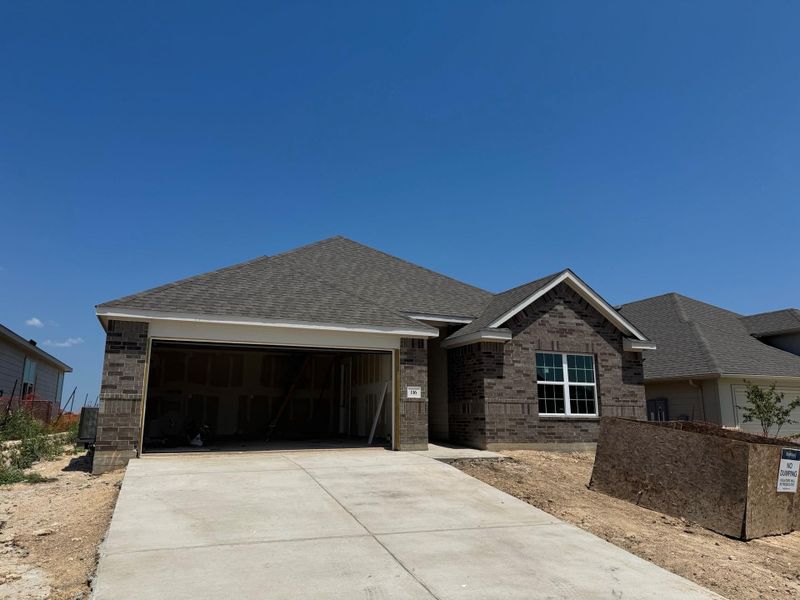 View of front of home featuring an attached garage, brick siding, roof with shingles, and concrete driveway