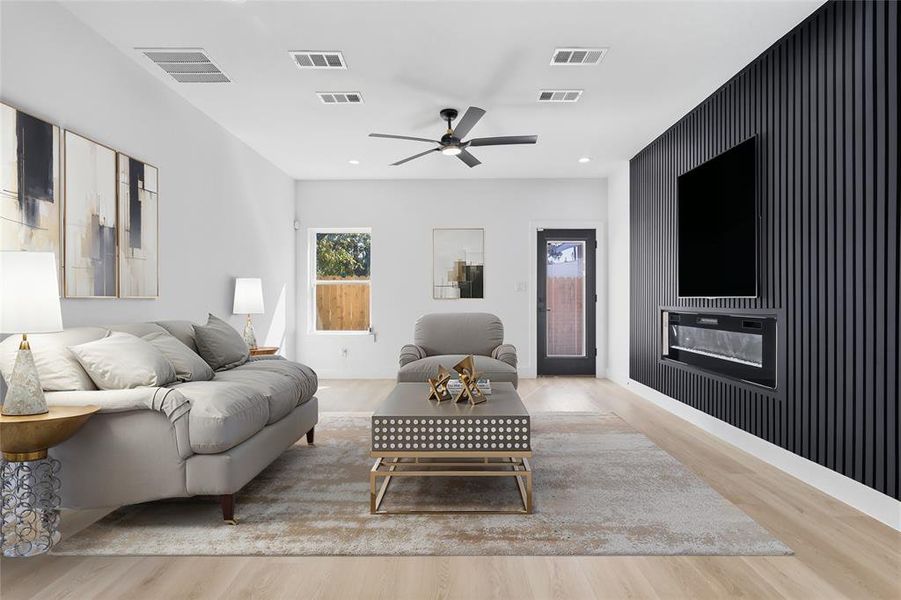 Living room featuring an accent wall, light wood-style floors, ceiling fan, and recessed lighting