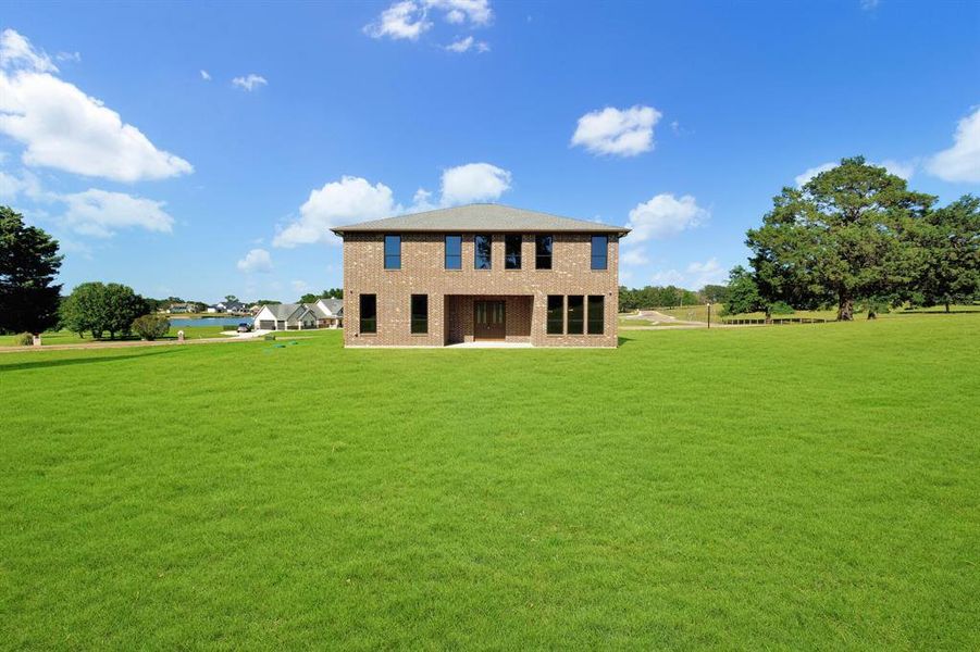 Two-story brick exterior residence featuring a gray shingled roof and multiple windows with dark frames Two-story brick exterior residence featuring a gray shingled roof and multiple windows with dark frames
