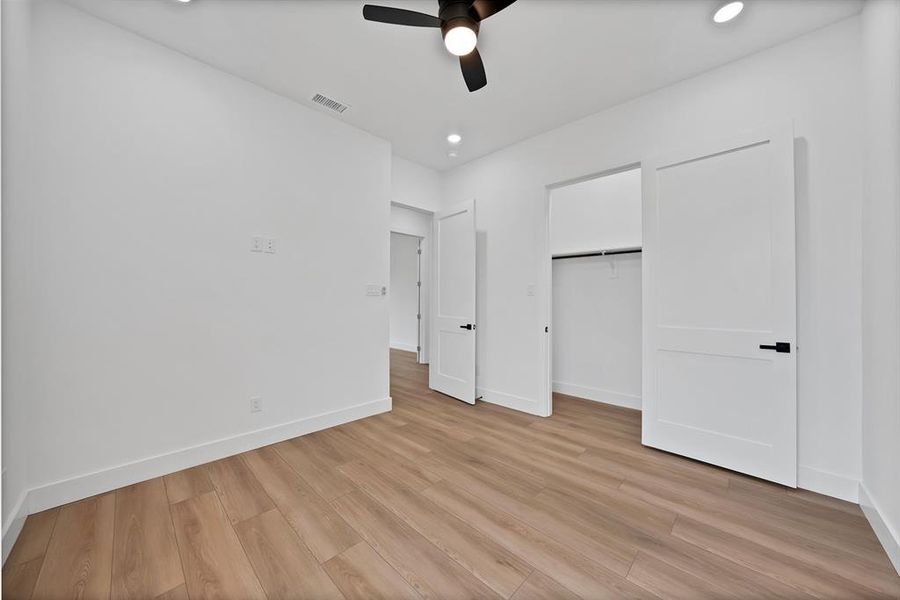 Spacious room featuring wood-finish flooring, recessed lighting, and a ceiling fan