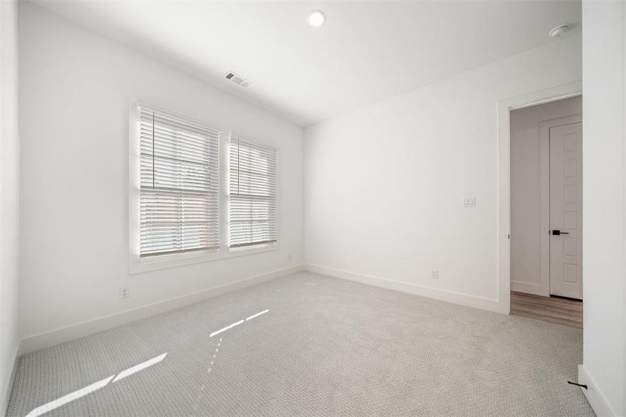 Empty room with light colored carpet and baseboards