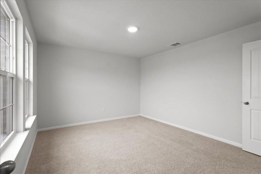 Carpeted interior space featuring white walls and trim, dual windows with white sills, a recessed ceiling light, and a paneled door with a round knob
