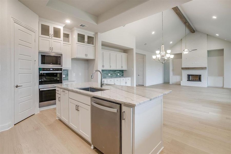 Kitchen with appliances with stainless steel finishes, a kitchen island with sink, and white cabinets