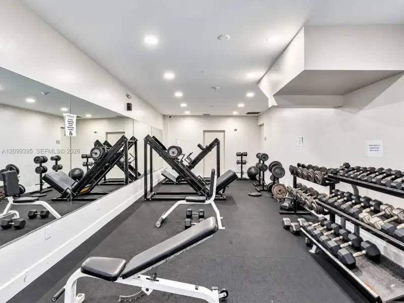 Fitness room featuring recessed lighting, wall-to-wall mirrored surfacing, and resilient rubberized flooring