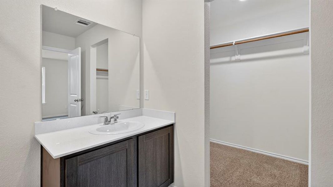 Bathroom vanity with a rectangular mirror, a built-in sink, and a white countertop, featuring dark wood-finish cabinetry