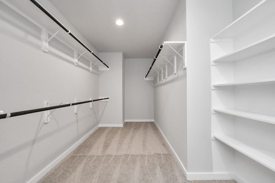 Spacious walk-in closet with high ceilings and plush carpet. Sample photo of completed home with similar floor plan. Actual colors and selections may vary.