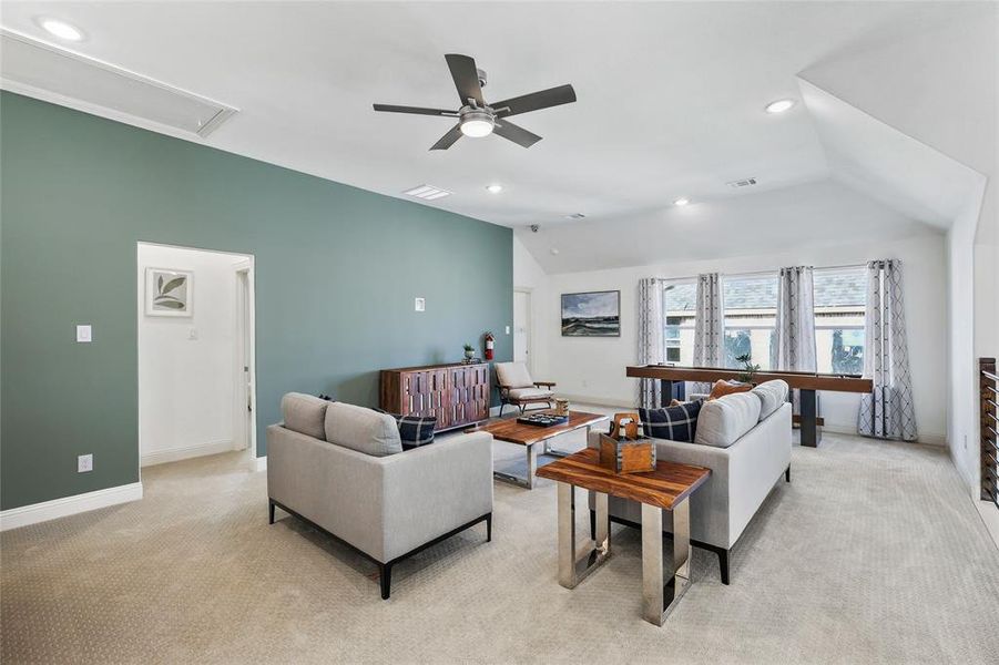 Spacious room featuring vaulted ceilings, recessed lighting, a ceiling fan, and carpeted flooring