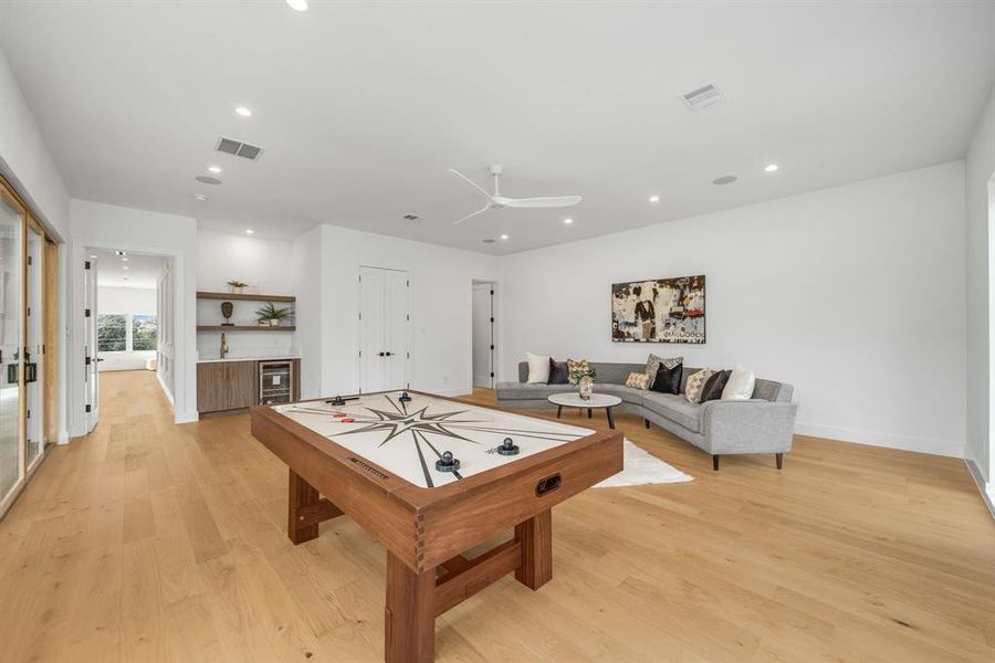 Playroom with a dry bar, recessed lighting, light wood-type flooring, and beverage cooler